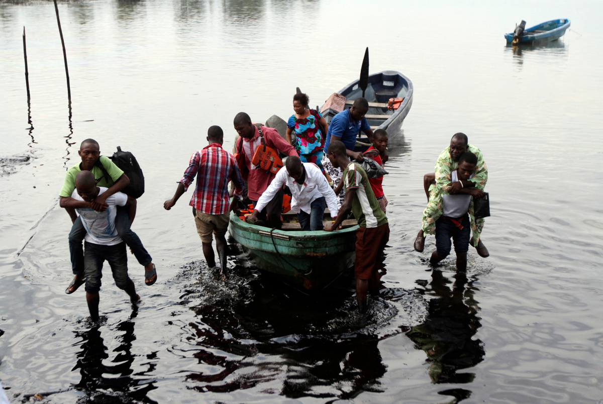 Boat guides carry people through polluted water as passengers disembark at the shore of Bodo creek in Ogoniland. December 4, 2012. REUTERS/Akintunde Akinleye