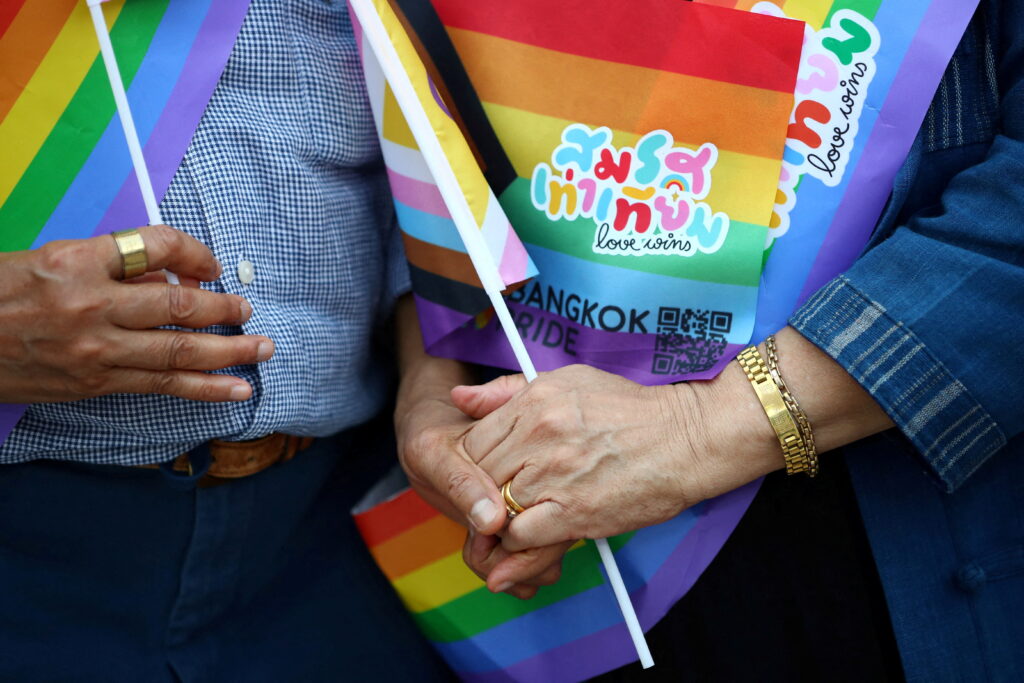 Pakodchakon Wongsupha, 67, and Kan Kerdmeemun, 73, hold hands and flags that read "Marriage equality, love wins", as they celebrate after the passing of the marriage equality bill in its second and third readings by the Senate, which will effectively make Thailand Asia's third territory to legalise same-sex unions, in Bangkok, Thailand, June 18, 2024.