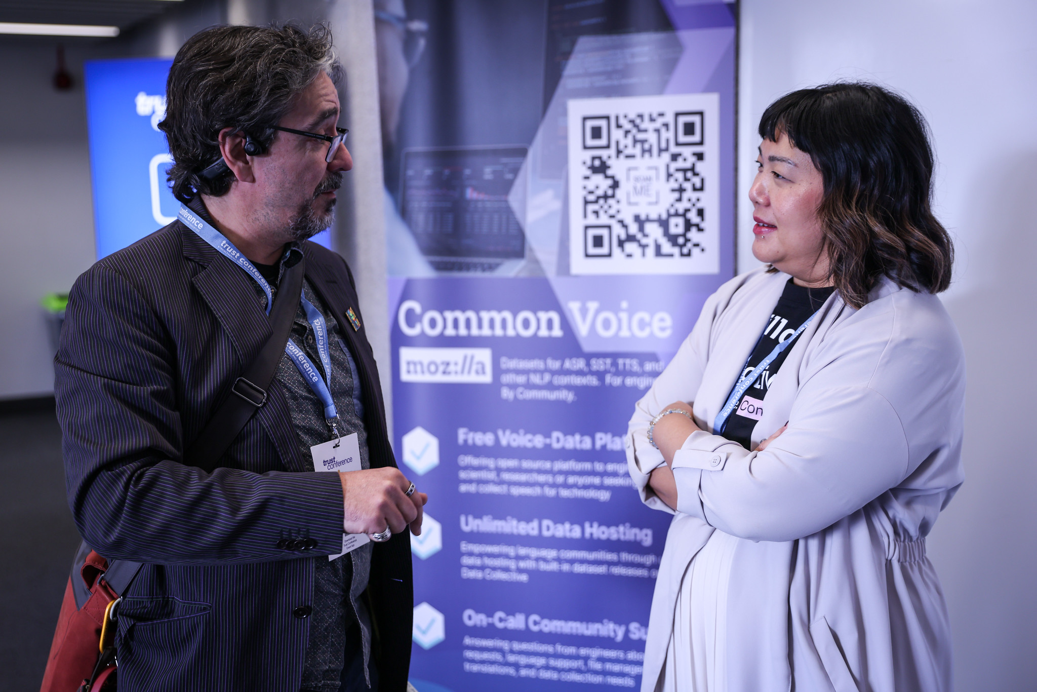 Two delegates chat in front of a sponsored board from Mozilla, our sponsor